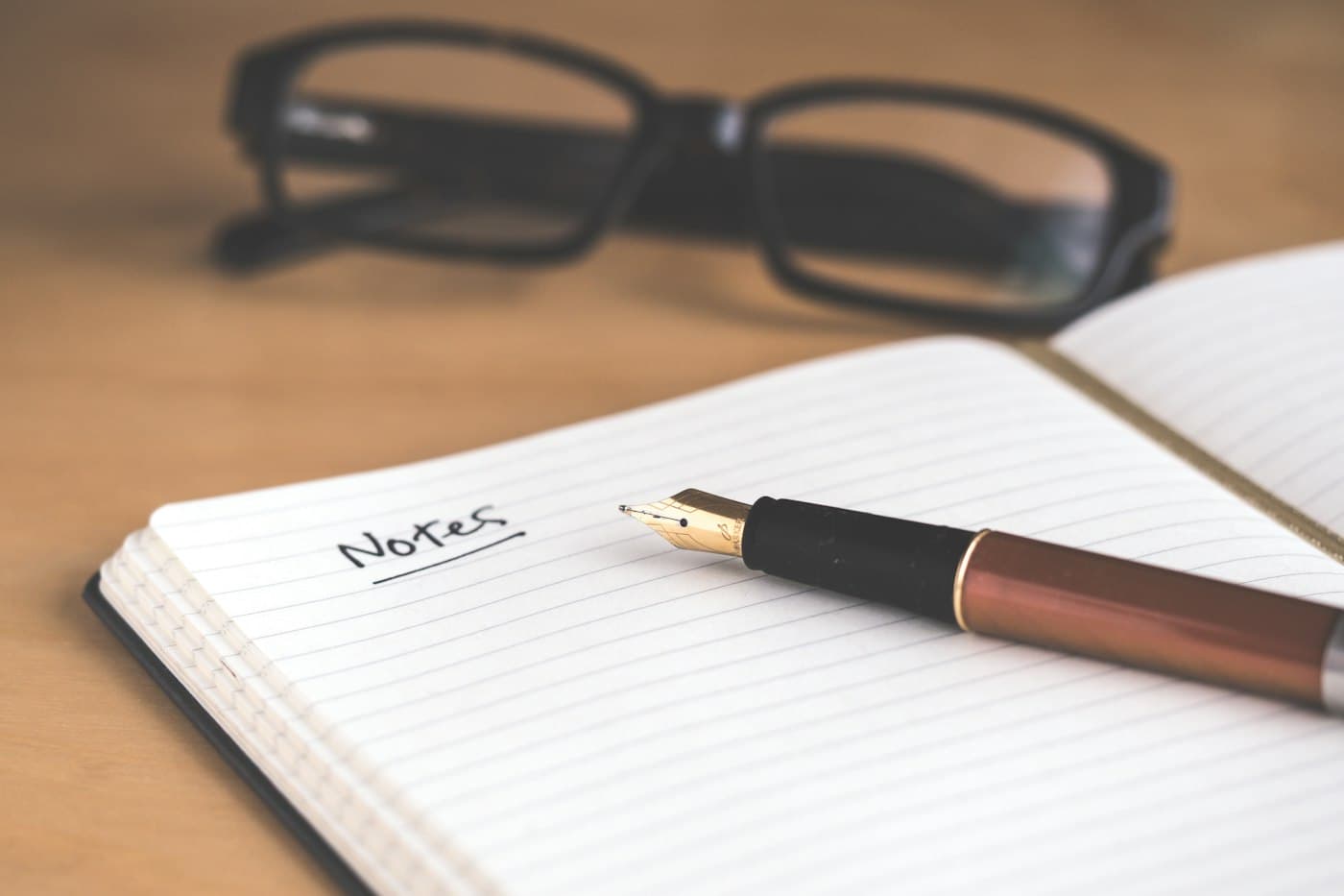 An open notebook with the word Notes written on it, a fountain pen across the page